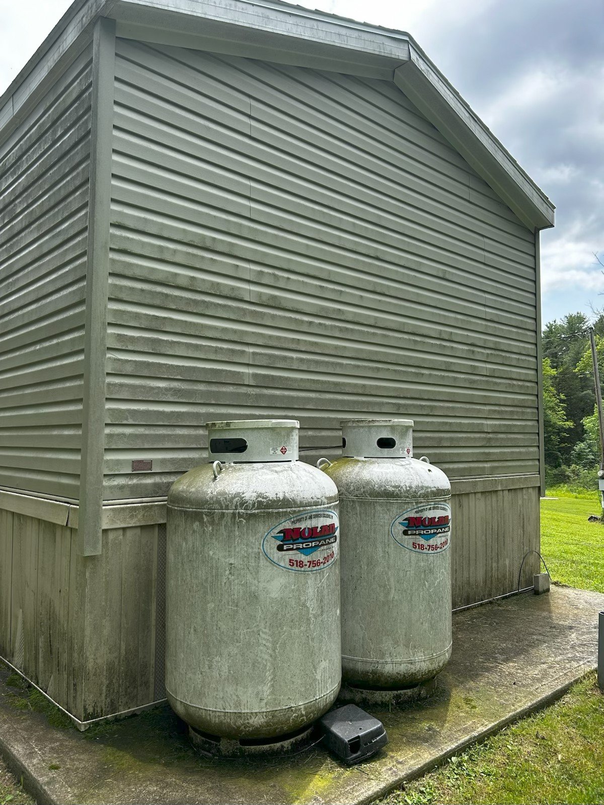 Dirty propane tanks and siding before cleaning